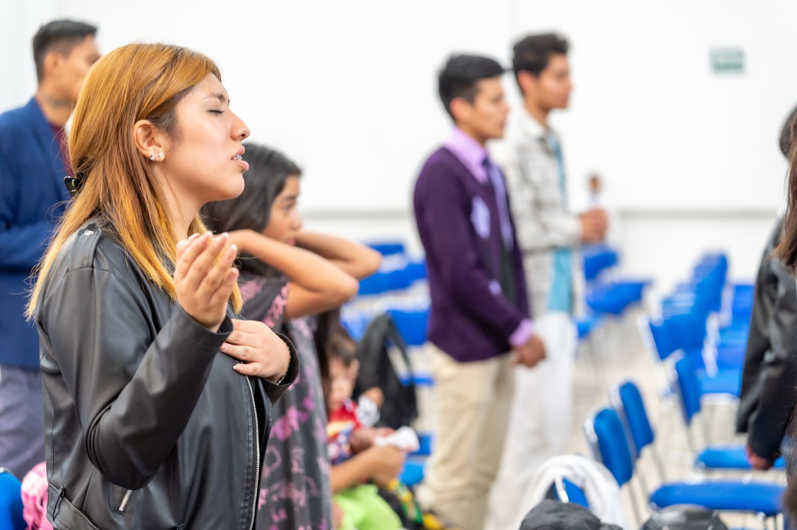 Jóvenes orando juntos durante un encuentro de la comunidad